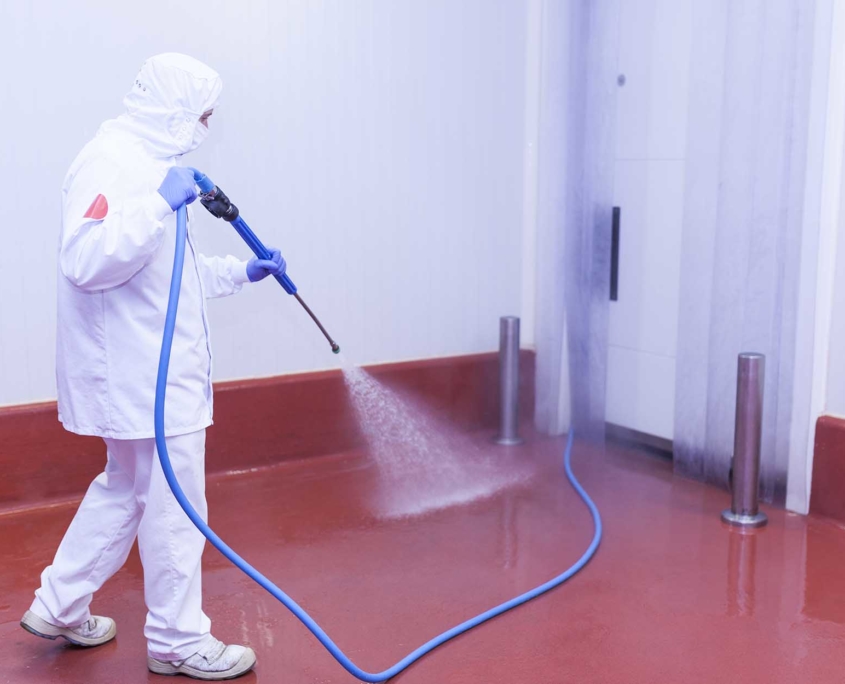 worker cleaning a facility with a power washer