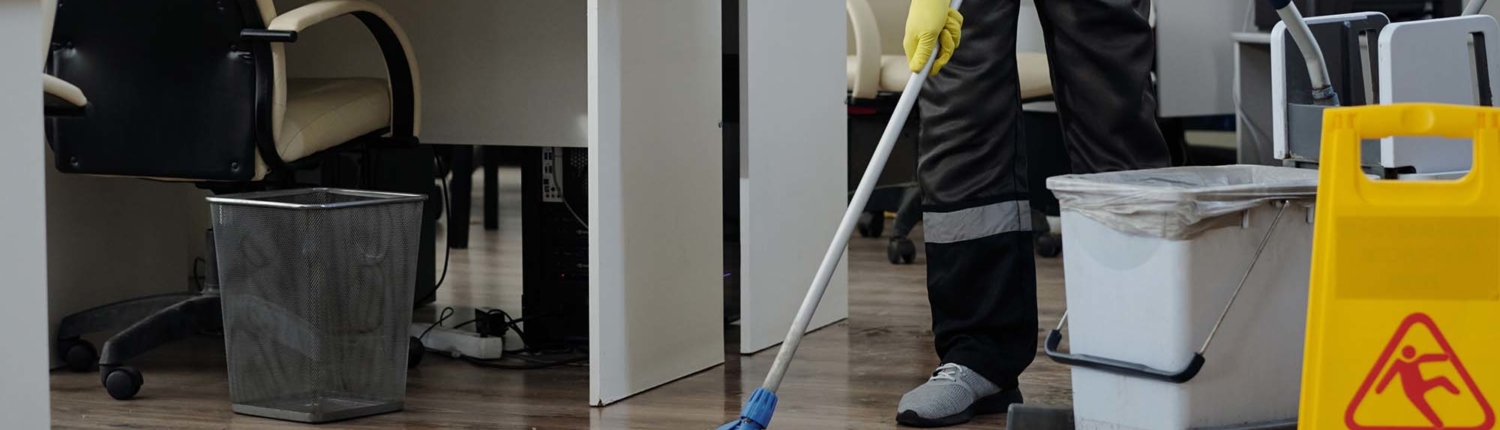 man in workwear cleaning floor in openspace office in