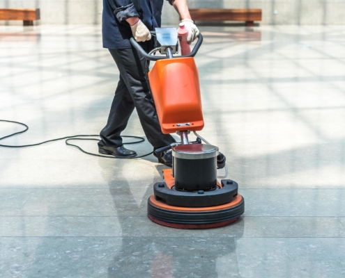 Image of a janitor buffing a tiled floor.