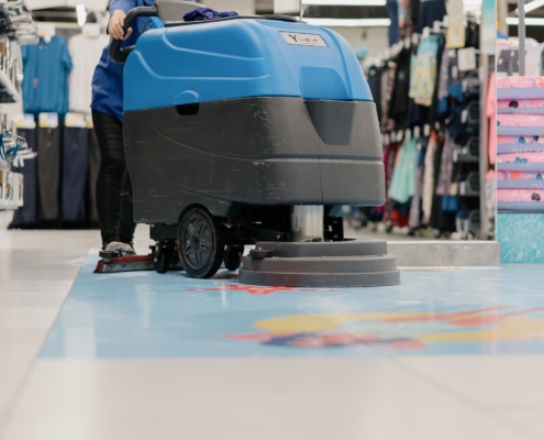 Image of a worker buffing tile floors in a retail store.
