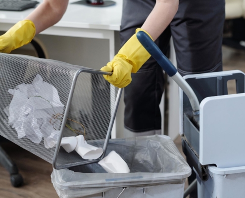 Image of a cleaning service person emptying office trash bins.