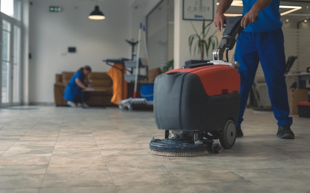 Image of a worker using a scrubber machine on a tile floor.