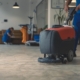 Image of a worker using a scrubber machine on a tile floor.