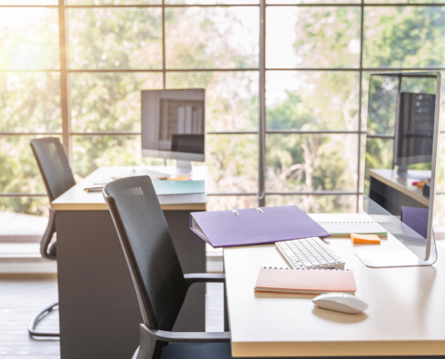 Side view of clean office desks with chairs and computers