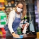 Image of a worker in a grocery store sanitizing a checkout counter.