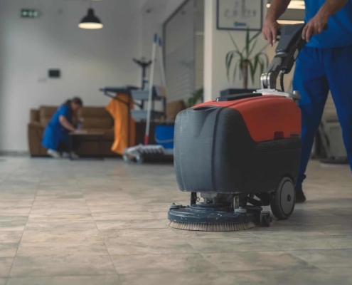 Image of a worker using a scrubber machine on a tile floor.