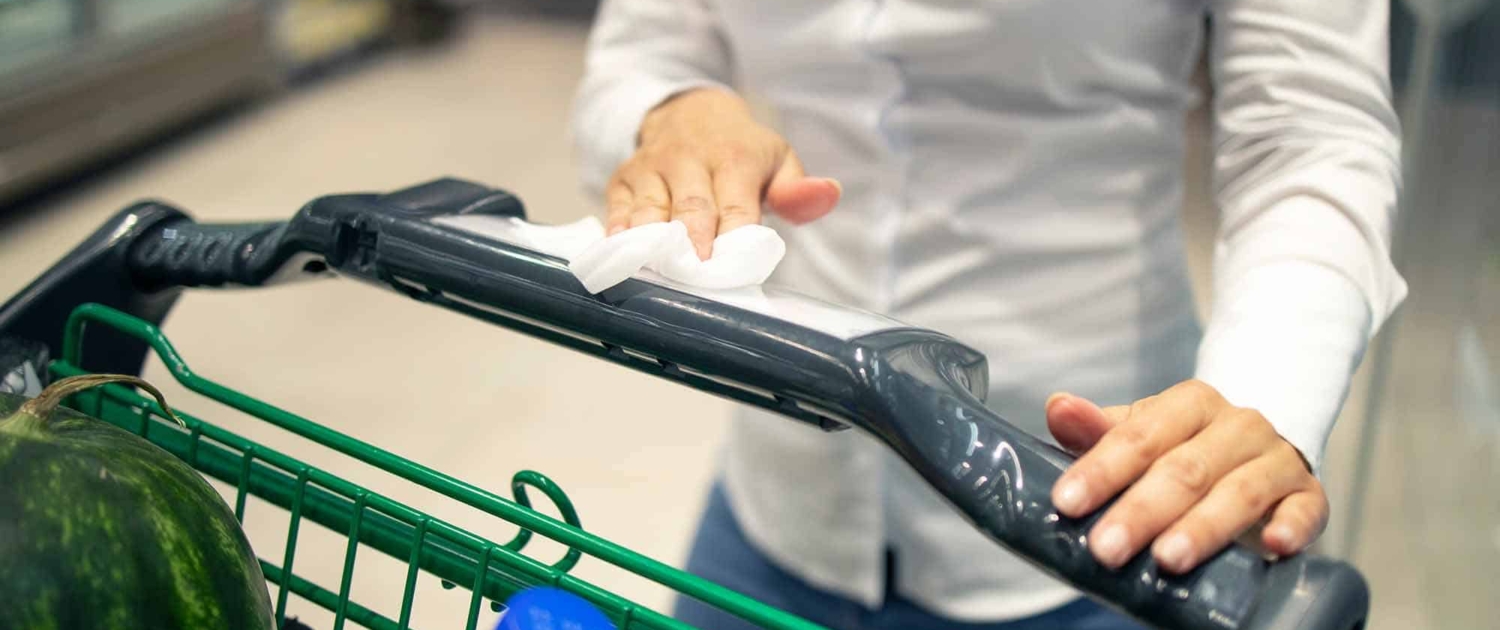 woman wiping a shopping cart