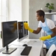 Professional cleaner wiping down computer monitors in office