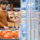 Man Opening Refrigerator In Supermarket While Shopping For Groceries