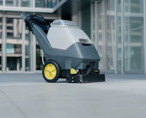 The Worker Is Using A Floor Scrubber To Clean The Floor